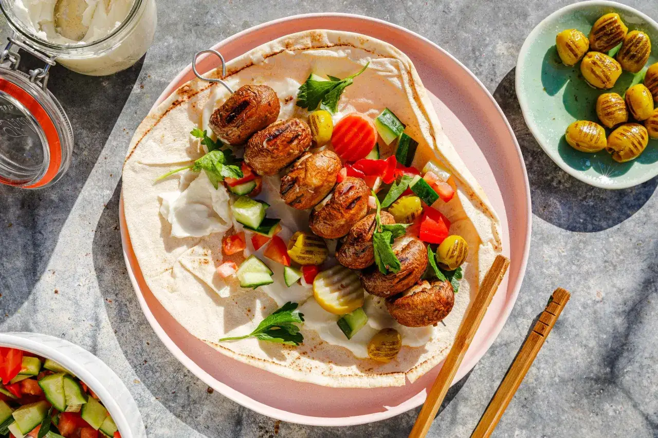 Gegrillte Champignon-Spieße auf Fladenbrot mit frischem Gemüse und Dip. Perfekt für vegane Grillrezepte!