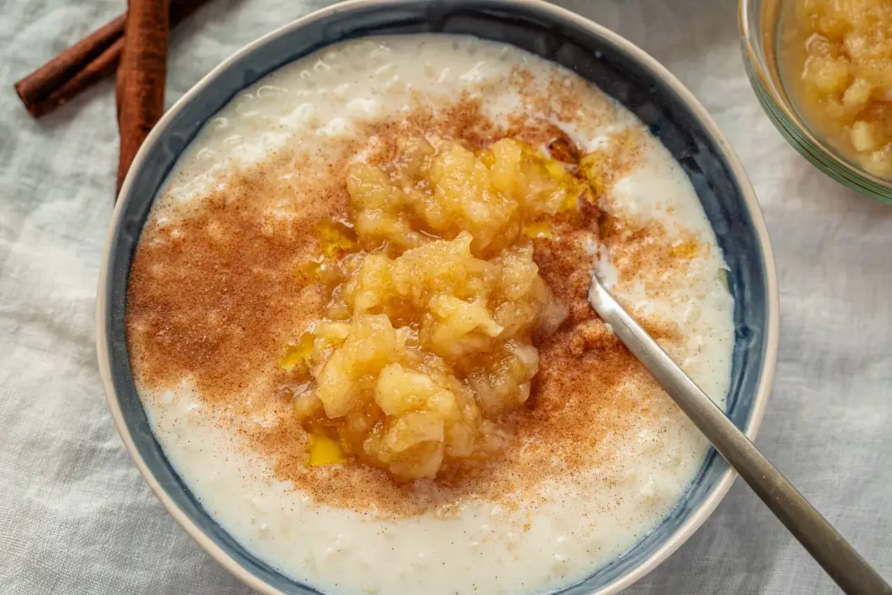 Cremiger Milchreis mit Apfelmus und Zimt, ein k&ouml;stliches reispudding rezept. Daneben liegen Zimtstangen.