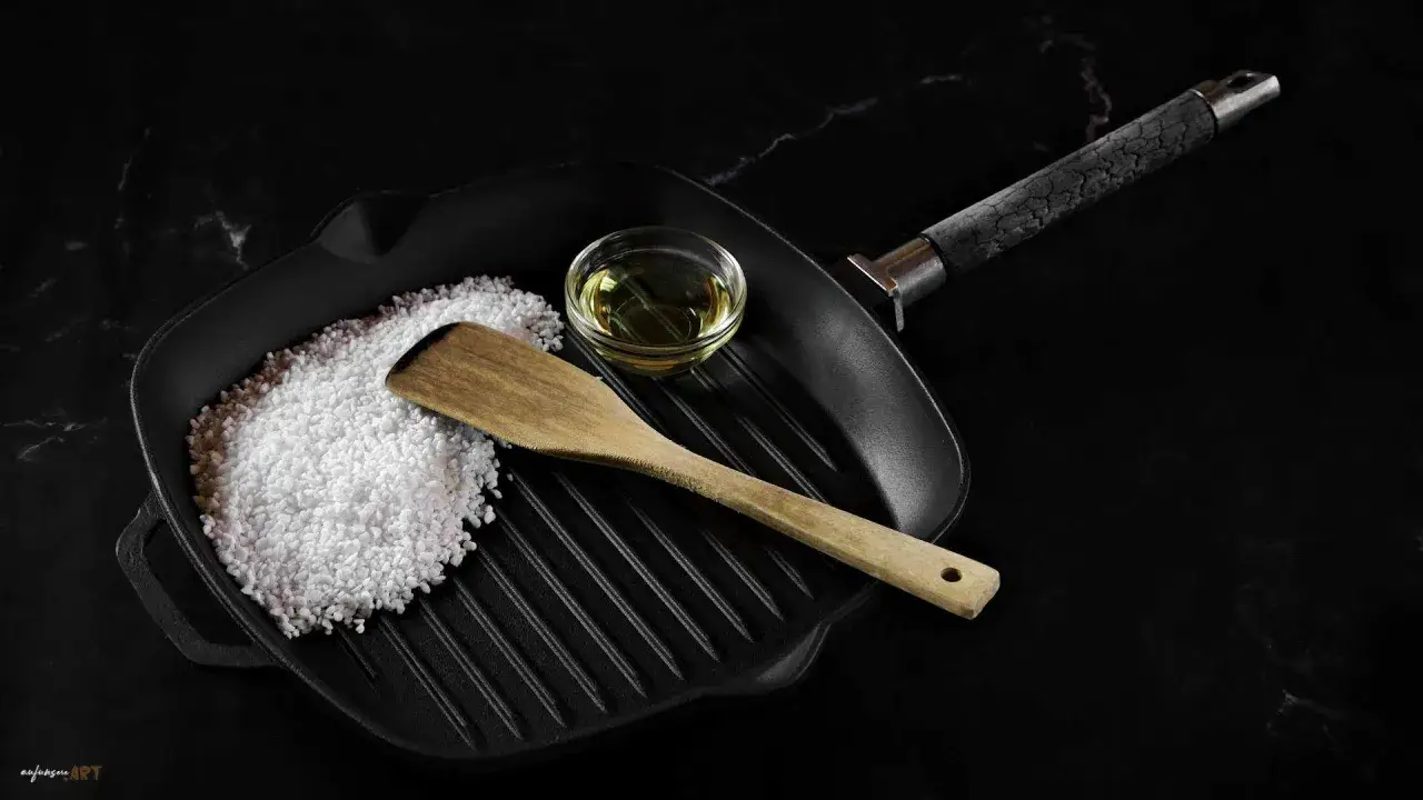 Gusseisenpfanne mit Salz, Öl und Holzspatel für das Pfanne einbrennen.