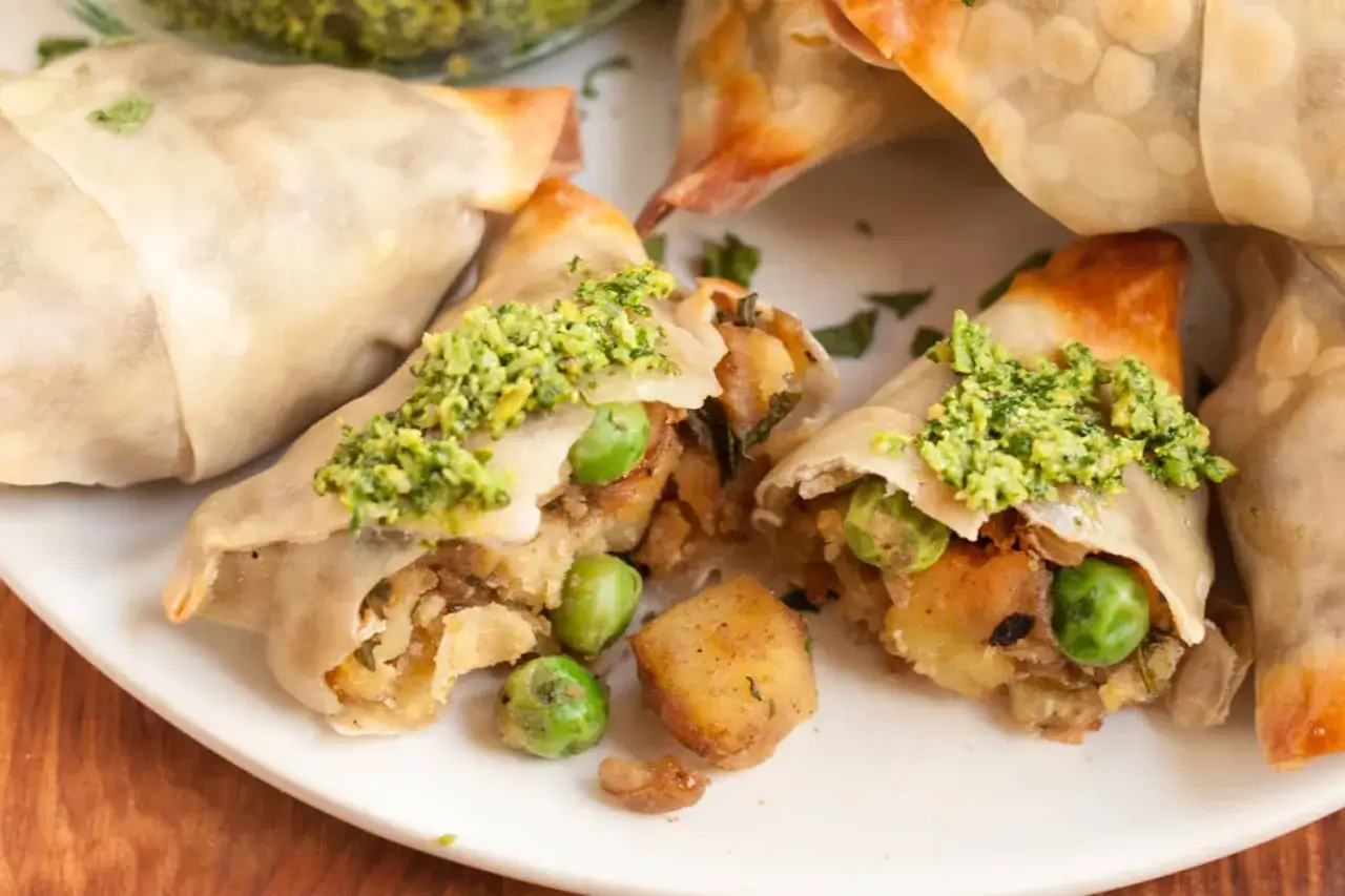 Leckeres samosa rezept: goldbraune Teigtaschen gef&uuml;llt mit Kartoffeln, Erbsen und Kr&auml;utern, garniert mit gr&uuml;ner Paste.