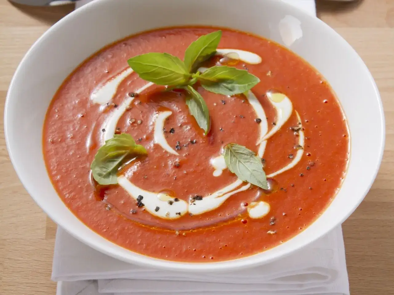 Ein cremiges Tomatensuppe Rezept mit frischen Tomaten, garniert mit Basilikum und einem Klecks Sahne.