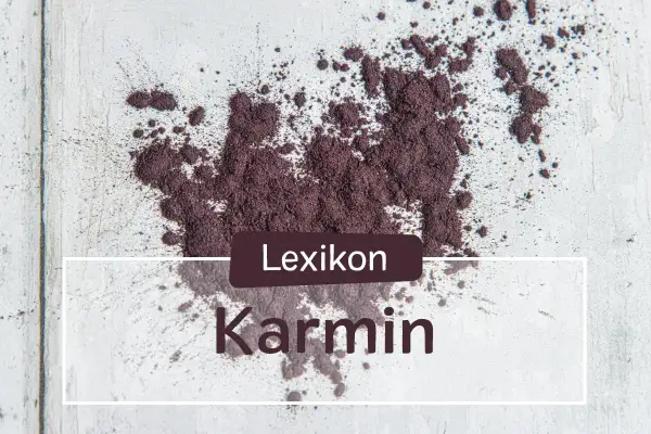 Ein Haufen echtes Karmin-Pulver, das auf einer hellen Oberfläche verstreut ist. Der Text "Lexikon Karmin" ist überlagert.