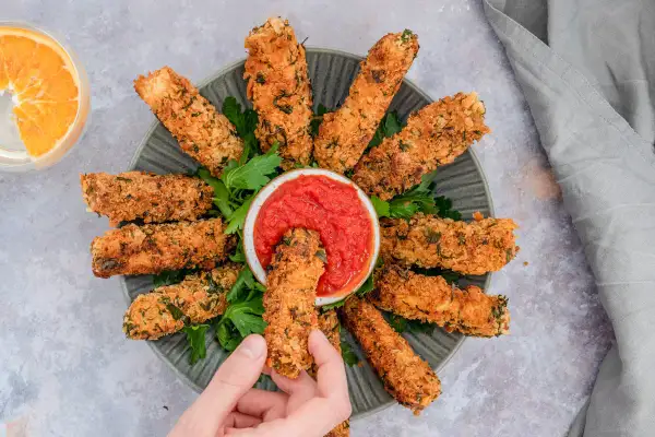 Knusprig paniertes Tofu, goldbraun gebacken, wird mit einer Schale Tomatensoße serviert. Ein perfekter Snack für alle, die Tofu panieren lieben.