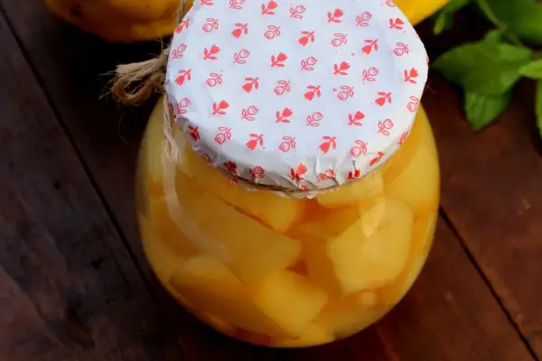Ein Glas mit leckerem Quittenkompott, liebevoll mit einem gemusterten Papier und Juteband verschlossen.