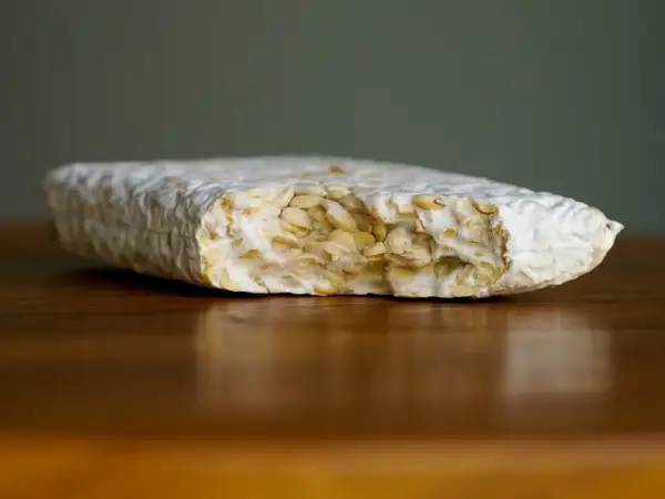 Ein Block Tempeh liegt auf einem Holztisch. Perfekt, um ihn für später einzufrieren.