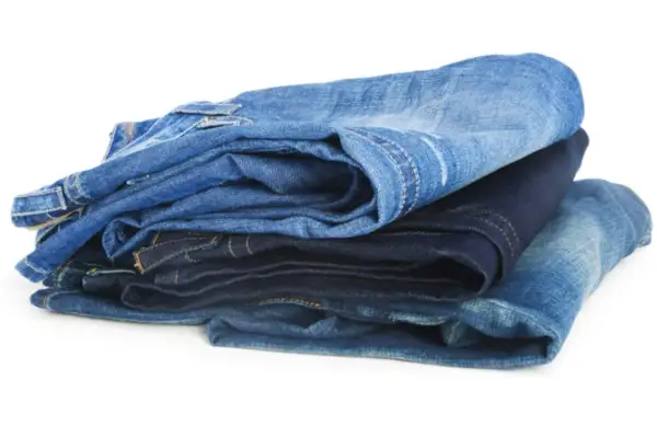 Gestapelte Jeans in verschiedenen Blautönen. Die Herstellung von Jeans verbraucht viel Wasser.