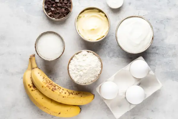 Reife Bananen, Mehl, Zucker, Butter, Eier, Schokolade und Joghurt – alles bereit, um die Bananen zu verwerten und etwas Leckeres zu backen.