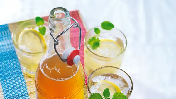 Erfrischender zitronenmelisse sirup in einer Bügelflasche, serviert mit Eis, Zitronenscheiben und Minze in Gläsern.